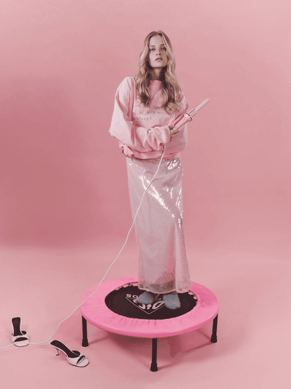 Woman on a pink trampoline with a pink background